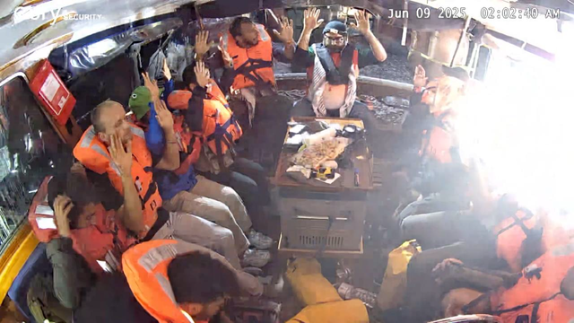 Last image sent by Madleen security camera. Crew with hands in the air. A blinding light on one side of the boat. Time stamp reads: June 09 2025 02:02:40 AM