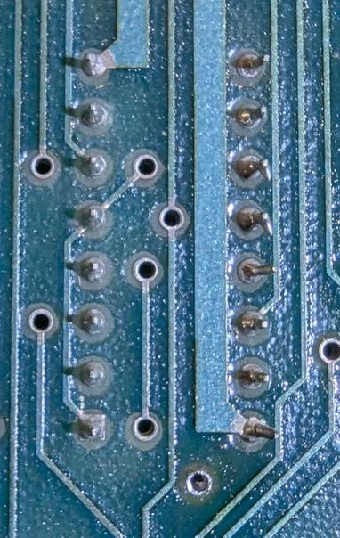 Closeup of the solder side of the board for a 16-pin chip, showing the original soldering job.