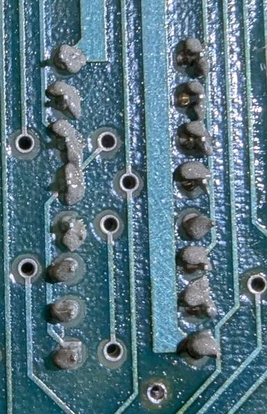 Closeup of the solder side of the board for a 16-pin chip, showing ChipQuik solder having been added, but not yet reflowed.