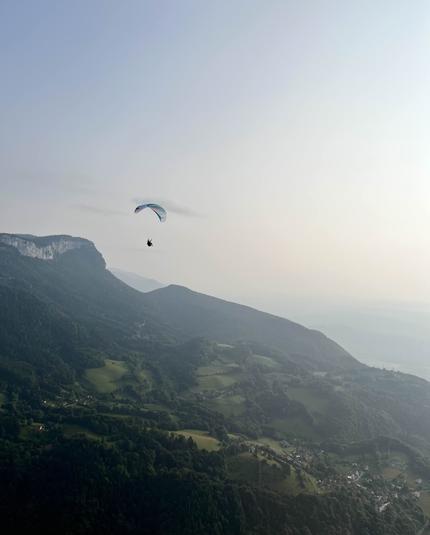 Photo d'un parapentiste haut dans le ciel devant une montagne.