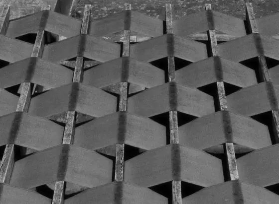 Alternating wrapped fabric in a geometric pattern around wooden planks in a high contrast dark shot.
