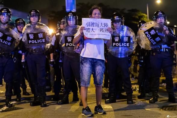 A well known activist known as female 'Long hair' standing in front of police holding an anti extradition bill banner.