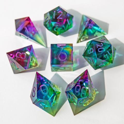 Hier ist wieder das ganze bunte Set auf weißem Untergrund zu sehen. Im vordergrund und im Fokus liegen D10 und D00, die Würfel sind mit der höchsten Seite nach oben um den D6 angeordnet. Die Würfel im Hintergrund sind etwas unscharf abgebildet.