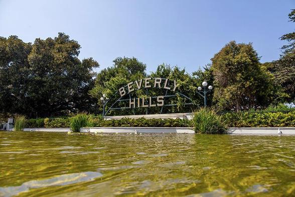 The iconic Beverly Hills sign nestled among lush greenery, a symbol of luxury and glamour in Los Angeles.
