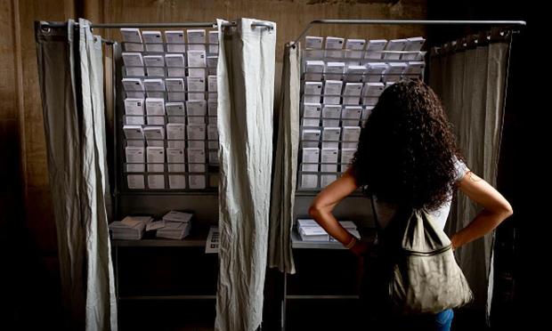 Una mujer ante una cabina de votación de las elecciones europeas del 9J de 2024, en Barcelona. (Albert Llop/NurPhoto via Getty Images)
