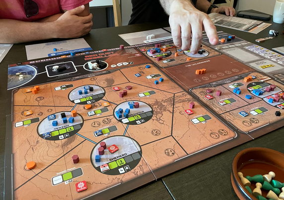 A game board on a table. It's mostly red, as it represents the surface of Mars. There are lots of different colored wooden bits on the game board as well.
