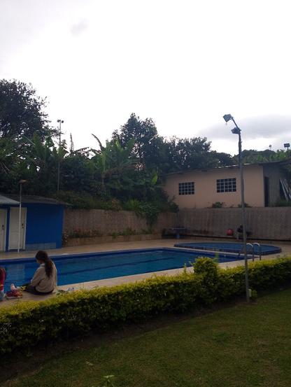 Piscina y una chica al lado y el cielo se encuentra nublado