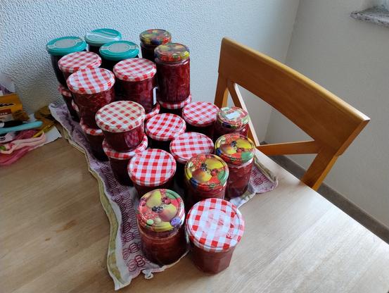 Etliche Gläser mit Marmelade die zum Teil aufeinander auf einem Küchentisch stehen.