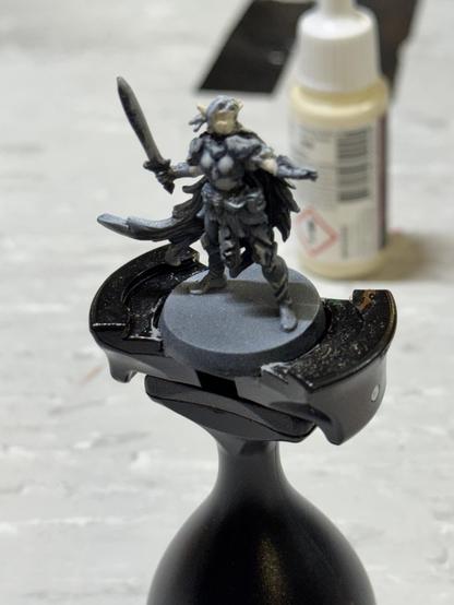 The elf hero character of HeroQuest on a painting handle. The mini started from a black primer and a white zenithal. In the first step I painted a darker blue grey.