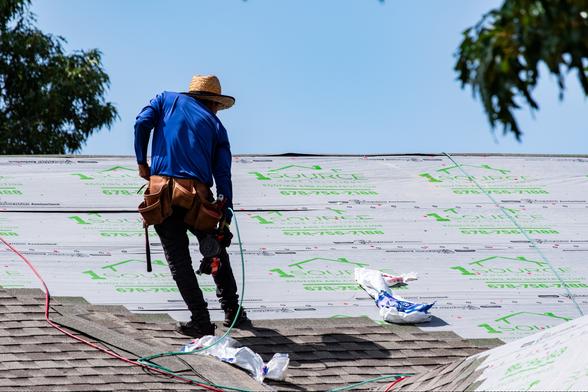 A roofer photographed from the second floor balcony of the next building over which gives the photo a little more of a straight on perspective.
