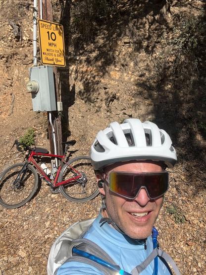 Selfie of me in front of my red bike leaning up against utility pole at top of sulphur mtn