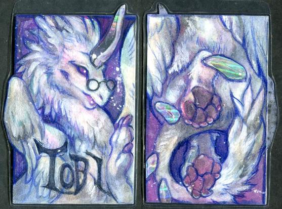 Watercolor badge with front and back side, of a white dragon with holofoil horn spines. The name reads Tobi.