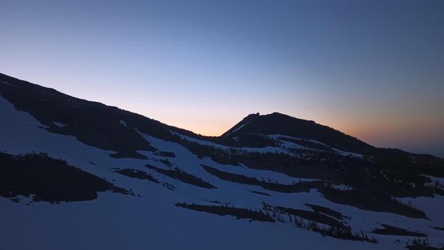 Looking at an eastern ridge just before sunrise. The sky is just starting to turn orange along the edge of the ridge.