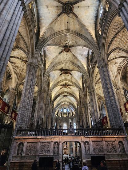 view down the center of the cathedral from the entrance to the altar. most of the view is of the high ceiling with ribbed vaulting.