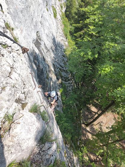Junger Mensch in Klettermontur auf dem Klettersteig, von oben aufgenommen.