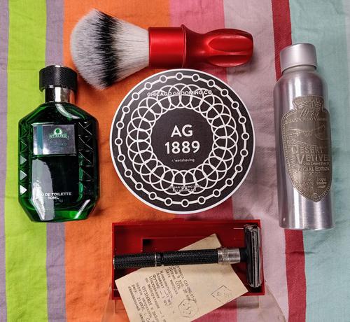 (Le Chat Mistral description)

The image showcases a collection of grooming items arranged on a striped background. At the top left, there is a green bottle of cologne labelled "Eau de Toilette." Next to it, a circular container from the "Chicago Grooming Co." with "AG 1889" printed on it. Above these items, there is a shaving brush with a red handle. To the right of the circular container, there is a metallic bottle labelled "Desert Vetiver."

At the bottom of the image, there is a safety razor in a red box, accompanied by a small piece of paper with text on it. The items are neatly arranged, suggesting a well-organised grooming kit.