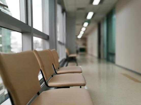 Stock photograph from Pexels.com that depicts a row of chairs in a waiting room adjacent to a clinic or medical offices.