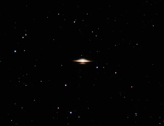 This is a photograph of M104, the Sombrero Galaxy, seen edge-on from Earth. With its thick bulge and resemblance to a hat, it resembles a hat. Numerous stars of various colors and brightness litter the scene.
