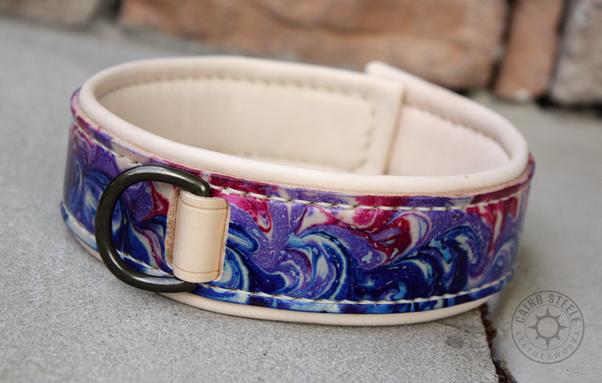 A handmade leather collar. The base strap is marbled dark blue, purple, and magenta (bi flag colors). The liner and top strap are natural, the stitching is cream, and the hardware is antique brass. The top strap is woven between the base strap and liner without using rivets.