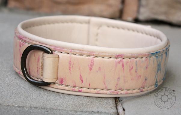 A handmade leather collar. The base strap is mostly natural beige leather with light pink and blue marbling (trans flag colors). The liner and top strap are natural, the stitching is cream, and the hardware is antique brass. The top strap is woven between the base strap and liner without using rivets.