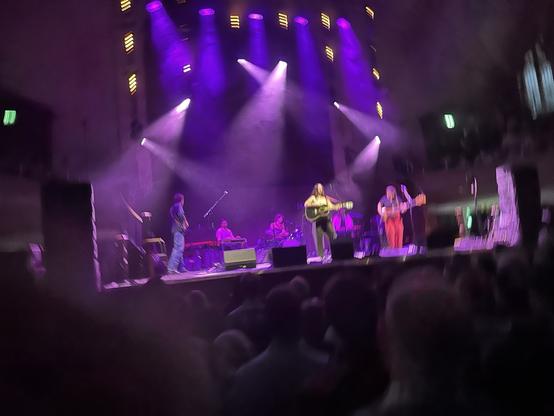 Waxahatchee live on stage at the Albert Hall in Manchester, seen from the crowd, the band bathed in purple and lilac light