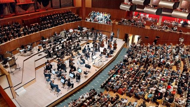 The hall, filling.  The choir, seated; the orchestra, arriving.