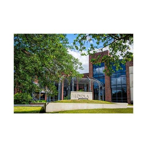 Entrance Loyola sign in the foreground and building complex framed by trees. Photography by Debra Martz