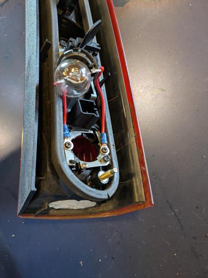 A taillight assembly removed from a car. One of the bulb holders has had two wires soldered to the terminals. The opposite ends of the wires are screwed down to metal parts of the taillight assembly.