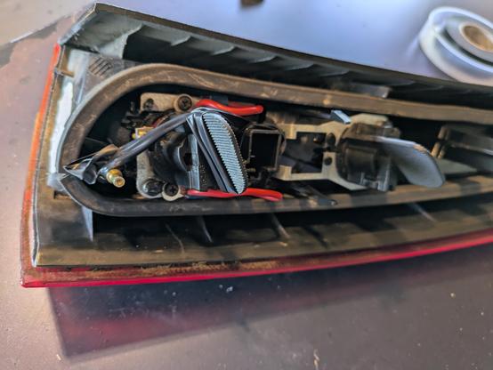 A taillight assembly removed from a car. Some psycho has wired in the brake light holder with a soldering gun and then used electrical tape to more or less hold it together.