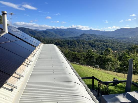 The view from the upper floor of our house out over the Brogo River valley. Part of our solar array is visible on the left, as is our chimney. To the right you can see our deck and part of the back yard.
From close to far distance, is some open farmland on a neighbouring block surrounded by forested hills, the heavily forested hills around the Brogo Dam, and furthest away, the heavy forest of the Wadbilliga National Park. Everything is crowned by a deep blue sky with cumulus clouds capping the distant mountains that form the foothills of the Snowy Mountains.