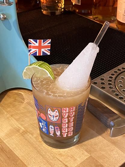 Navy Grog in a Navy Strength, Seattle Mai Tai glass, garnished with a patterned lime wedge, Union Jack, and grog cone.