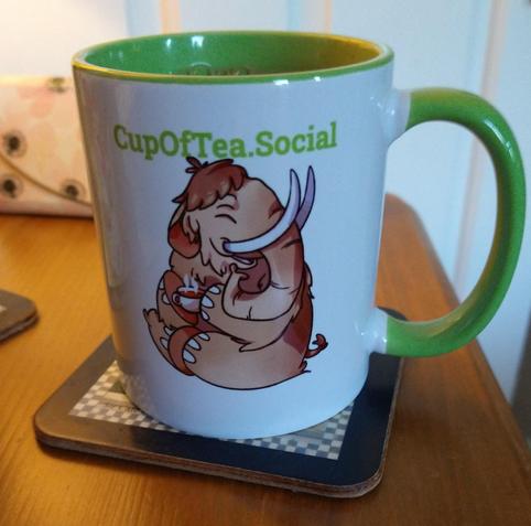 Green cupofteasocial mug on a bedside cabinet