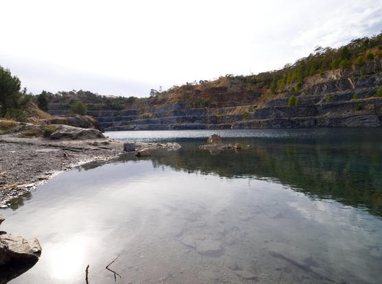 A lake in a bluestone quarry in Adelaide's north-eastern suburbs. The shot has been taken down low, close to the water, so the mostly-overcast sky is reflected in the water.