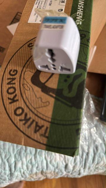 Nothing like a Chinese-to-North American power adapter taped to the box to inspire confidence. A white AC plug adapter is stuck to a cardboard box using packing tape. Fortunately, the device in the box can charge with USB-C, so I don’t need to use this.