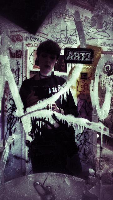 extremely grungy mirror selfie with graffiti everywhere and a sticker saying ARTZ