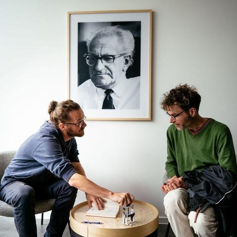 Arne Semsrott signiert das Buch eines Gastes. Im Hintergrund ein Proträt von Fritz Bauer.