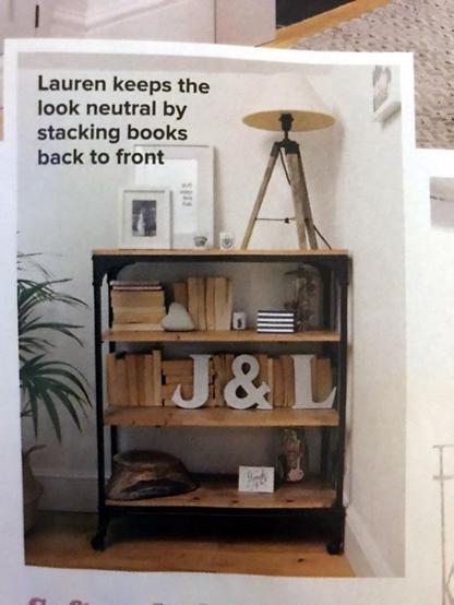 A bookshelf from a magazine where the spines of the books are turned away. Overlaid text reads: "Lauren keeps the look neutral by stacking books back to front"