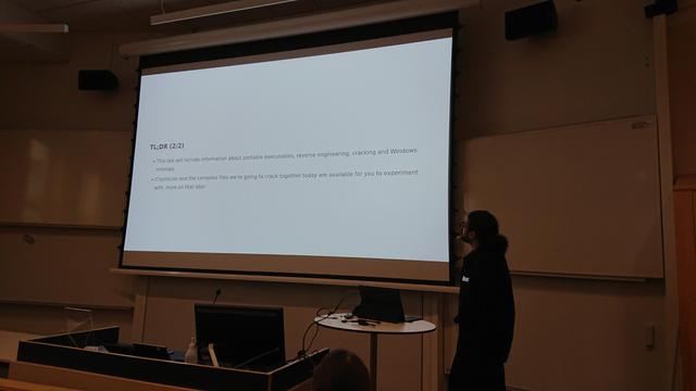 A lecture slide outlining the topics of the talk, including: portable executables, reverse engineering, cracking and Windows executables