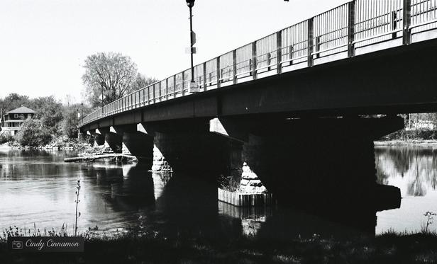 Pont sur une rivière. Photographie en noir et blanc par Cindy Cinnamon