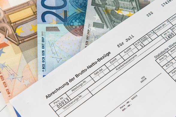 Bild einer beispielhaften Abrechnung der Brutto-Netto-Bezüge, die auf Euro-Banknoten liegt