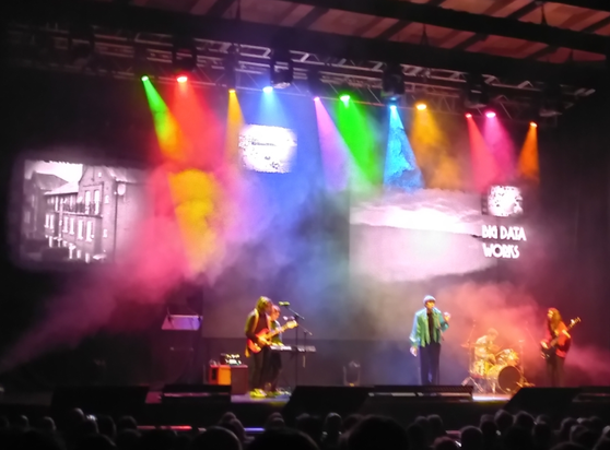 View of the enlighted stage of Brighton Dome with five musicians (vocals, guitar, bass, keyboard, drums) from BIMM University playing an intro piece.