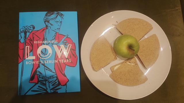 Copy of Low, a graphic memoir of David Bowie, next to a plate of oatcakes and an apple
