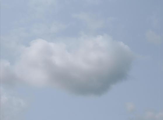 Fluffy white cloud against a light blue sky, with smaller cloud formations in the background.