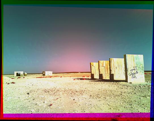 Several delapidated buildings in the desert in the false color of an IR trichrome.