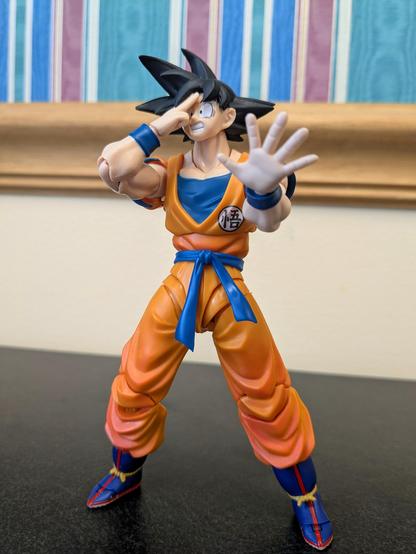 S. H. Figuarts Goku preparing to Instant Transmission away with an embarrassed look on his face and his left hand out in a placating gesture