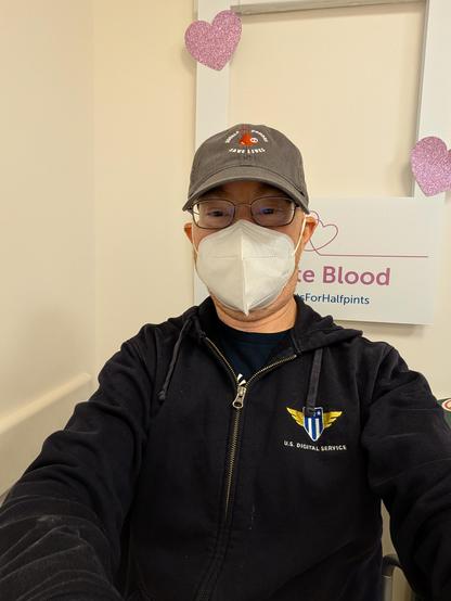 Middle-aged white guy wearing glasses, an ear-loop KN95 mask, a black U.S. Digital Service hoodie, and a baseball cap with the words "double red donors save lives" embroidered into the front in a circle around a red drop-of-blood graphic with "X2" on it