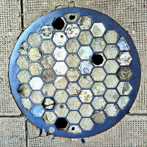 A manhole cover with a honeycomb design on it which would originally have been filled with prisms.