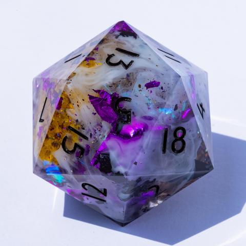 An oversized D20 with yellow flowers, purple metallic foil, white smokey swirls and black numbers.
