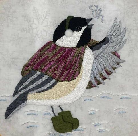 Embroidered chickadee wearing s winter cloak, ear muffs, and green winter boots. She is singing, with beak open and one wing outstretched.