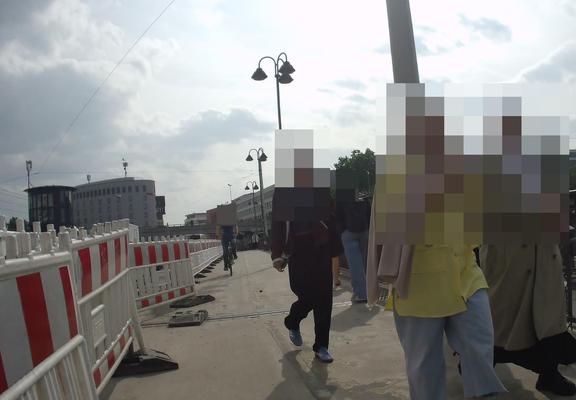 Sicht auf den schmalen Radweg, es kommt ein Radfahrender entgegen, rechts auf dem Gehweg sind mehrere Personen unterwegs, es ist sehr eng.